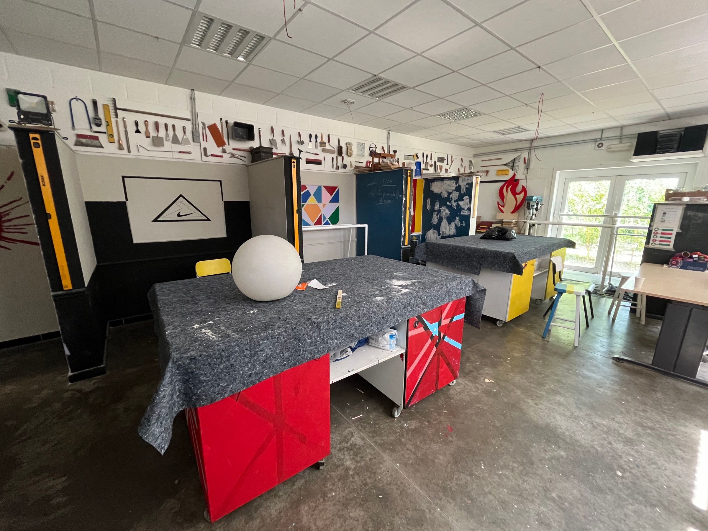 Atelier de peinture de l'école, tables de travail et matériel accroché au mur