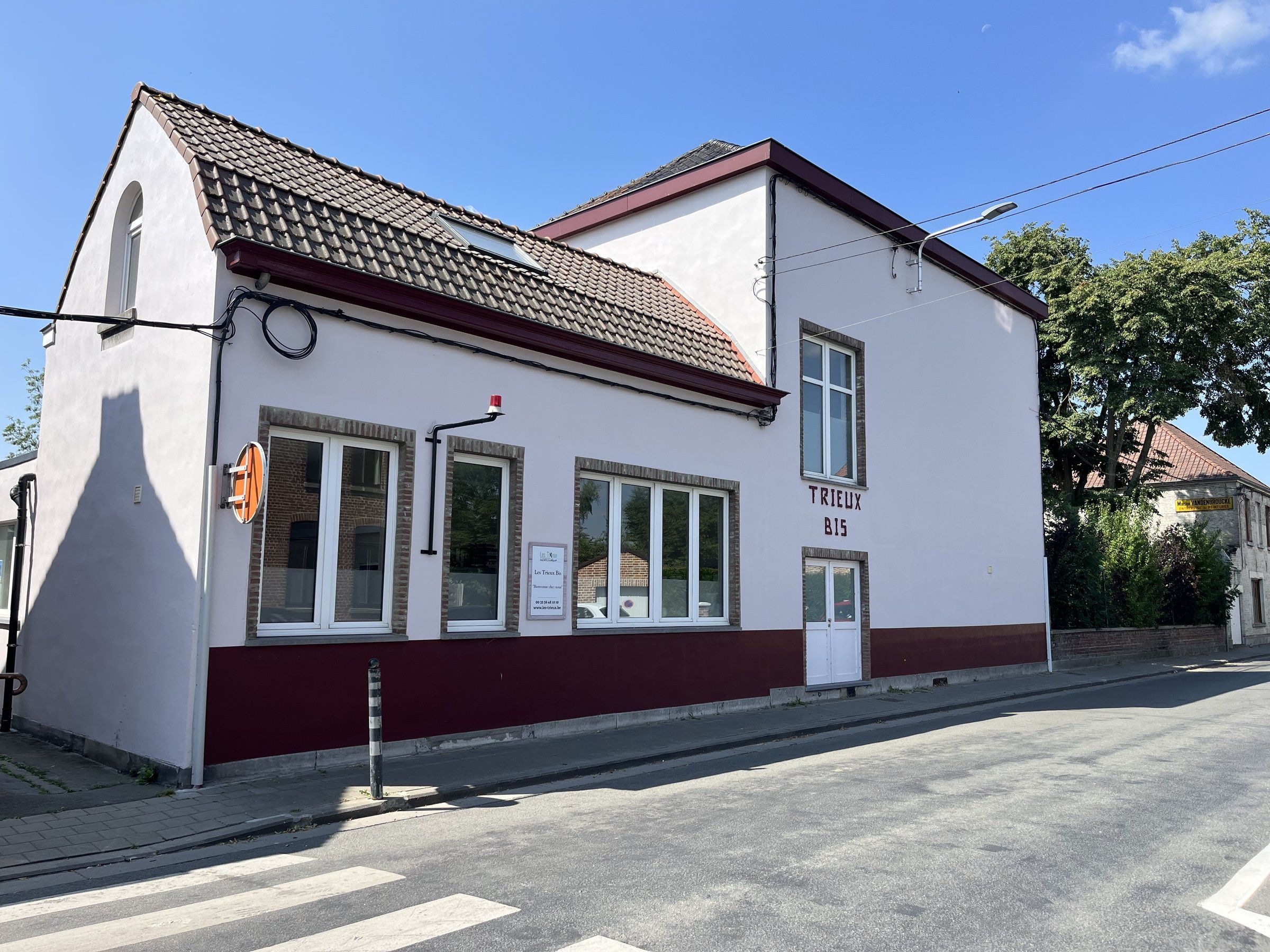 Façade du Trieux Bis, bâtiment blanc à soubassement bordeaux portant son enseigne